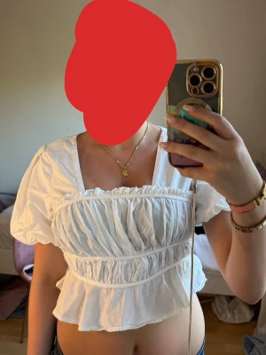 Vit blus med puffärm från NA-KD - Supersöt vit blus från NA-KD med puffiga korta ärmar och volang nedtill. Toppen har rynkade detaljer över bysten och midjan som ger en romantisk vibe. Perfekt att styla med jeans eller kjol för en trendig look.