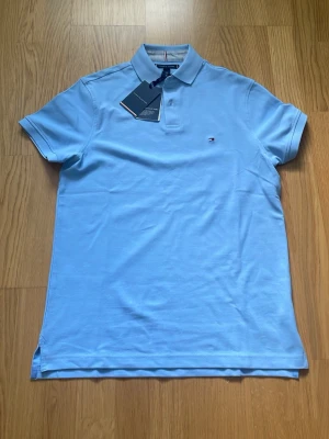 Ljusblå Piké från Tommy Hilfiger - Helt ny och oanvänd piké i ljusblå färg från Tommy Hilfiger. Skick: 10/10. Storlek: S (regular fit) , Pris: 299 (förhandlingsbart!!)