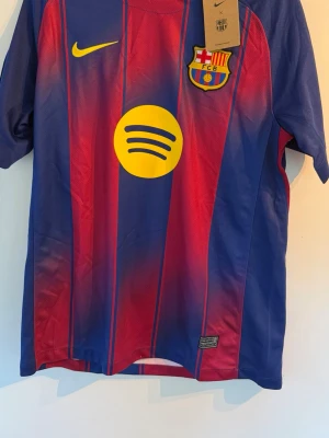 FC Barcelona matchtröja Lamine Yamal 25/26 - Snygg FC Barcelona matchtröja från Nike i blått och rött med gula detaljer. Tröjan har klubbmärke, sponsorlogga och nummer 10 med Lamine Yamal på ryggen. Tillverkad i lätt och ventilerande material, perfekt för fotbollsträning eller match.