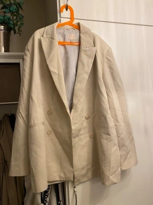 Beige oversized kavaj från H&M - Stilren beige kavaj från H&M i oversized modell med dubbelknäppning . Mycket fint skick 