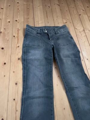 Low waist bootcut jeans - Snygga grå bootcut jeans med två framfickor och klassisk knappgylf. Jeansen har en lätt tvättad look och raka ben som går ut lite nedtill. Perfekta för en avslappnad och trendig stil. Jag är 165cm och dom går ända ner till fötterna på mig