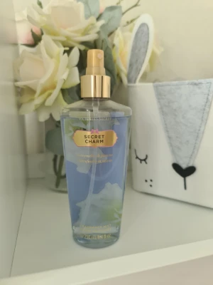 Victoria's Secret Secret Charm mist - Fräsch body mist från Victoria's Secret i doften Secret Charm. Flaskan är transparent med ljusblå vätska och har guldfärgad spraypump. Doften har inslag av kaprifol och jasmin. Volymen är 250 ml och flaskan är i plast. Minns inte vad den luktade som ny. Säljer nu av min vintage kollektion. Perfekt för samlare. Eftersom dofterna är vintage kan lukten skilja sig markant från nya, och köps därmed på eget bevåg.