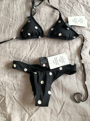 Svart polka dot bikini från HM - Snygg svart bikini med vita prickar och klassisk trekantbikini.