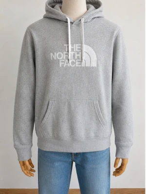 Grå hoodie från The North Face - Snygg grå hoodie från The North Face med vit logga framtill. Klassisk modell med huva och vita dragsnören samt en stor magficka. Tillverkad i mjukt material som är skönt att ha på sig. Perfekt för en avslappnad och sportig stil.