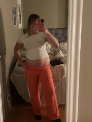 Coral byxor - Säljer ett par orange mjukisbyxor med utsvängda ben och låg midja. Byxorna är i mjukt och bekvämt material, perfekta för en avslappnad stil. Passar dig som gillar färg och vill ha något skönt att chilla i.
