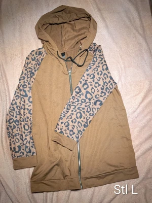 Brun hoodie med leopardärmar - Säljer en brun hoodie med leopardmönster. I nyskick. Finns i Holmsund men kan skickas mot porto.