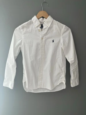 Vit Ralph Lauren skjorta - Tjena!                                                                              Säljer denna feta vita Ralph Lauren skjortan då den är för liten för mig. Storlek 140-146. Perfekt nu till sommarn för kanske bara de stilig ut eller att ha till någons student. Nypris 1000kr från kidsbrandstore. Har kanske haft den i ett och ett halvt år men hann inte använda den mycket då den blev för liten. Vid frågar är det bara attskriva MVH Lukas