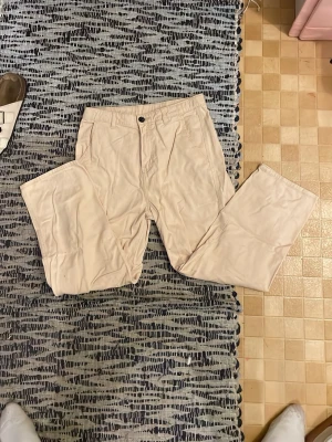 Beiga raka jeans - Säljer ett par beiga jeans med rak passform och klassisk femficksdesign. Jeansen har normal midja och stängs med knapp och dragkedja. Perfekta för en clean och avslappnad stil.