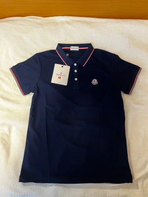 Marinblå pikétröja från Moncler - Helt ny, oanvänd! Bredd 48cm, höjd 64cm. 