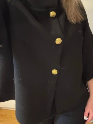 Trekvartsärmad kappa med guld knappar - Trekvartsärmad kappa med guldknappar, one size. Passar mig som brukar ha s-m. Använd kanske en gång, köpt för 599 från hem och trend. Säljer för 250