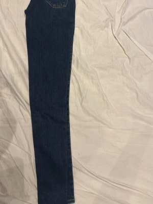 Mörkblå skinny Levi’s jeans W23 L30 - Säljer ett par mörkblå skinny jeans med klassisk femficksdesign och hög midja. Jeansen har smal passform hela vägen ner och är tillverkade i ett stretchigt denimtyg som sitter snyggt på benen. Perfekta för en trendig och enkel look.