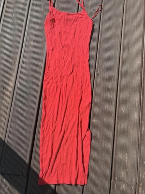 Röd långklänning från Amisu - Säljer en röd långklänning från Amisu med smala axelband och figurnära passform. Klänningen är enkel och stilren, perfekt för sommardagar. Materialet är mjukt och stretchigt, vilket gör den bekväm att bära.