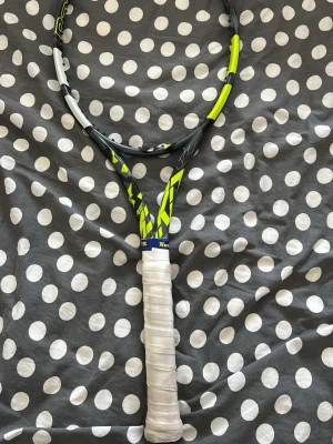 Babolat tennisracket svart/gul - Säljer en Babolat tennisracket i svart och gul design med vitt handtag. Racketen har en modern look och är tillverkad i slitstarkt material, perfekt för dig som gillar att spela tennis och vill ha en snygg och sportig racket. Ram 98 305g.
