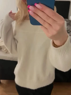 Vit  stickad tröja - Mysig vit stickad tröja med oversized passform och bred ribbad kant vid hals, ärmslut och nederkant. Perfekt för lager på lager och enkel att styla till olika outfits. Tröjan har långa ärmar och är gjord i ett mjukt material.