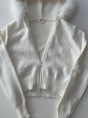 Zip hoodie med päls luva - En krämvit zip hoodie ifrån Gina Tricot i Stolek xxs med päls luva. Den är helt ny utan prislapp 