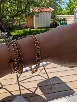 Bismarck armband i stainless steel  - Snyggt armband i guldig metall med breda, platta länkar i en klassisk kedjedesign. Armbandet har ett robust lås och passar perfekt för att ge din outfit en trendig touch. Perfekt för dig som gillar stilrena accessoarer med lite edge.