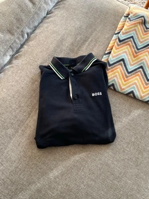 Svart piké från boss  - Tjena säljer denna svarta pikén från Boss. Den saknar den mittersta knappen men om man kan sy är de enkelt att få dit en extra! Strl:S hör gärna av er om ni är intresserade