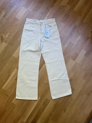 Perfect wide jeans från Gina tricot  - Säljer ett par beige linnebyxor från Weekday med raka ben och klassisk femficksdesign. Byxorna har hög midja och är tillverkade i ett mjukt linnematerial som känns luftigt och skönt. Perfekta för en avslappnad och trendig look.