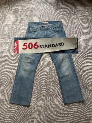 Levi's 506 blå raka jeans - Säljer ett par klassiska blå Levi's 506 jeans med rak passform och snyggt slitna detaljer. Jeansen har fem fickor, knappgylf och är tillverkade i slitstark denim. Perfekta för en avslappnad och tidlös stil. Strlk W33L32 men passar snarare W31L32. Skriv om mått eller frågor!