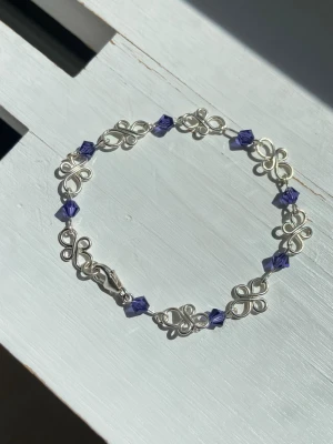 Handgjort 925 sterling silver armband med mörklila göaspärlor - Handgjort 925 silver armband av mig. Pärlorna är 4 mm mörklila tjeckiska glas MC bicone pärlor Formerna är lödda på baksidan som ni kan se på Den sista bilden för hållbarhet och design. Längd på armband: ca 16,5 cm Tråd tjocklek på formerna: 0,8 mm Tråd tjocklek där pärlan sitter: 0,6 mm Kolla gärna in mina andra annonser då jag ofta säljer liknande armband och smycken💕✨