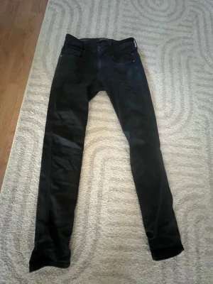 Svarta skinny jeans från Replay - Säljer ett par svarta skinny jeans från Replay, modell Hyperflex. Jeansen har klassisk femficksdesign, smal passform och stretchigt material som ger extra komfort. Perfekta för dig som gillar en tight och modern look.