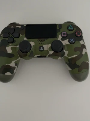 Kamouflage DualShock 4 handkontroll - Säljer en Sony DualShock 4 handkontroll till PlayStation 4 med snyggt kamouflagemönster i grönt, brunt och svart. Kontrollen har klassisk form med touchpad, analogspakar och PlayStation-knapp. Perfekt för gaming och ser riktigt cool ut!