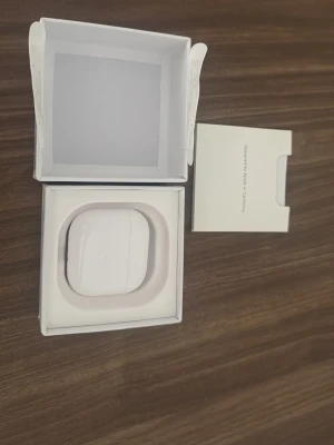 Apple AirPods med laddningsetui - Säljer ett par vita Apple AirPods med tillhörande laddningsetui. Snygg och stilren design i blank plast, perfekt för dig som vill ha trådlösa hörlurar med grym ljudkvalitet och enkel anslutning till iPhone eller andra Apple-enheter. Originalförpackning och manual medföljer.