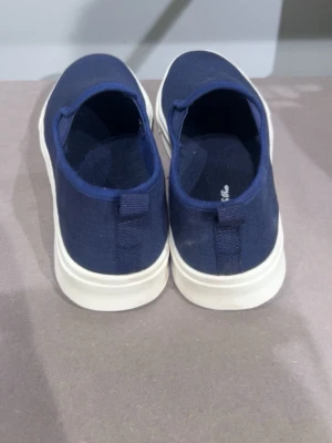 Marinblå slip-on sneakers - Snygga marinblå slip-on sneakers från Daniel & Peer med ovandel i canvas och vit, räfflad gummisula. Skorna har en enkel och clean design utan snörning, perfekt för en avslappnad stil. Tidlös modell som är lätt att matcha med olika outfits.