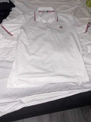 Vit Moncler pikétröja med röd detalj - Hej säljer min vita moncler pikee som är knappt använd har använt den 2 gånger den är i storlek M men passar bäst som S