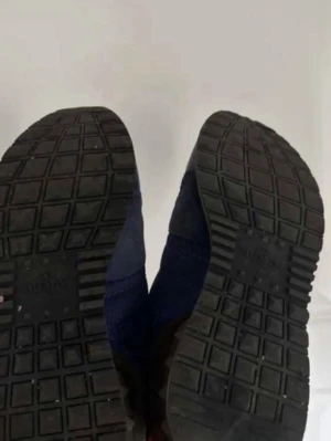 Blå rockrunners med rutmönstrad sula - Säljer ett par blå rockrunners sneakers med klassisk rutmönstrad svart sula. Skorna har en sportig look och är tillverkade i textil och syntetmaterial. Perfekta för dig som gillar streetwear och vill ha något bekvämt och stilrent.