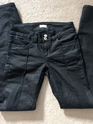 Svarta jeans från Relaxed - Snygga svarta jeans från Relaxed med raka ben och dubbla silverknappar i midjan. Klassisk femficksmodell med markerade sömmar framtill. Jeansen har en stilren look och passar perfekt till en trendig vardagsstil.