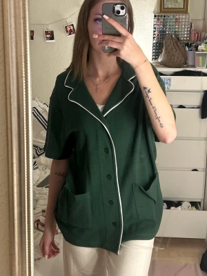 Grön ribbad skjorta ASOS DESIGN - Grön ”skjorta” från ASOS DESIGN i ribbat mjukt material med korta ärmar, knappar framtill och två stora fickor. Perfekt för att matcha till snygga outfits, men kan även användas som pyjamaströja. Aldrig använd!