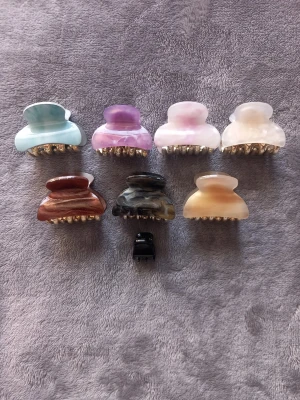 Färgglada hårklämmor i plast - Säljer ett set med sju hårklämmor i olika färger: ljusblå, lila, rosa, vit, brun, svart och beige. Klämmorna har en glansig finish och metallfärgade detaljer. Perfekta för att snabbt sätta upp håret och ge en snygg touch till din look. Den svartas handtag med möster har lossnat, men lätt att fixa tillbaka🖤. (Se enligt sista bild)