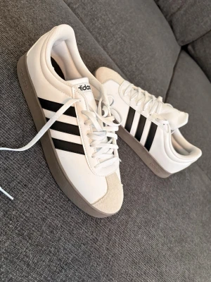 Vita Adidas sneakers med svarta ränder -  Helt nya snygga Adidas sneakers. Box och allting finns med skriv i dm för mer frågor 