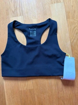 Svart sport-bh från Move - Säljer en svart sport-bh från Move med brottarrygg och elastiskt material. Perfekt för träning och aktivitet, med bekväm passform och stilren design. Lappen sitter kvar på bh:n.