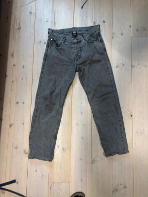 Gråa lösa jeans - Säljer ett par gråa jeans med rak passform och klassisk femficksdesign. Jeansen har en diskret tvättad look och är tillverkade i denim. Perfekta för dig som gillar en enkel och stilren stil. De har mindre skavanker vid insidan på båda benen men ingenting som märks vid användning (se bild). Kan tänka mig gå ner i pris vid snabb affär och tveka inte på att höra av dig vid funderingar!