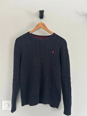 Mörkblå kabelstickad tröja Polo Ralph Lauren - Stickad Polo Ralph Lauren, använd ett par fåtal gånger så är i väldigt bra skick, inga märken eller skador någonstans.