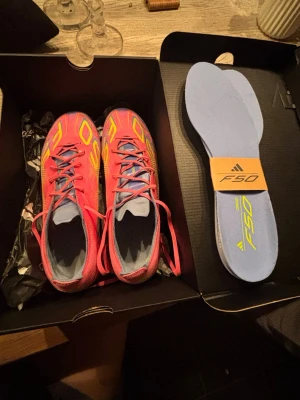 Adidas F50 rosa fotbollsskor FG - Säljer ett par Adidas F50 fotbollsskor i en riktigt snygg rosa och gul färg med blå detaljer och använda få tal gånger.Perfekta för dig som vill sticka ut på fotbollsplanen! Endast använda ca en vecka.