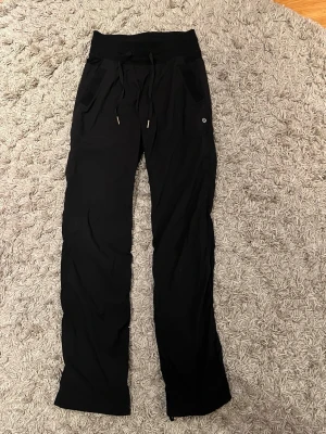 Svarta dance studio pants  från Lululemon - Snygga svarta träningsbyxor från Lululemon. Byxorna har två fickor framtill och är tillverkade i ett mjukt, stretchigt material som passar perfekt för gymmet, dans  eller yoga. Är även i tall, så extra långa i benen!