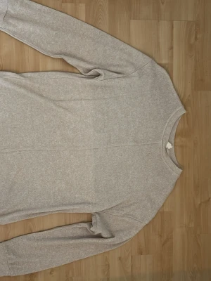 Ljusgrå sweatshirt med slits - En enkel och stilren ljusgrå sweatshirt med rund hals och långa ärmar. Tröjan har en rak passform och en liten slits i sidan nedtill. Perfekt för en avslappnad look och lätt att matcha med andra plagg.