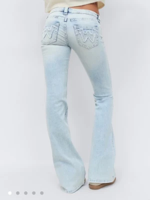 Ljusblå bootcut jeans från 14+ - Säljer ett par helt nya oanvända ljusblå bootcut jeans från 14+ med snygga broderade detaljer på bakfickorna. Helt slutsålda på hemsidan!