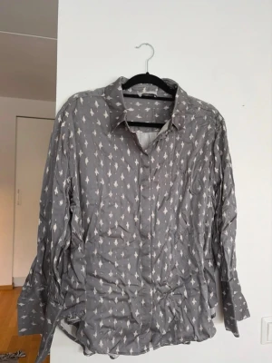 Skjortblus i satin från By Malina - En fin grå skjortblus i satin ifrån By Malina. Superfint skick! Storlek L men skulle säga att den är mer som en M