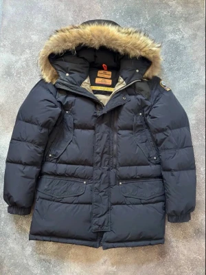 Svart dunjacka från Parajumpers - Säljer en svart dunjacka från Parajumpers med stor huva och päls. Jackan har flera fickor, dragkedja och tryckknappar framtill samt klassisk Parajumpers-logga på ärmen. Perfekt för kalla vinterdagar. Pris kan diskuteras. Hör av dig om du har frågor