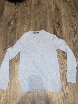 Ljusgrå basic tröja - En enkel och stilren ljusgrå tröja med rund halsringning och långa ärmar. Perfekt att matcha med jeans eller över en skjorta för en clean look. Tillverkad i mjukt material som känns skönt mot huden.