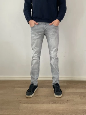 Jack and Jones Jeans - Säljer ett par fräscha gråa jack and jones jeans  för endast 299kr!                                                                             Nypris:899kr därav väldigt bra erbjudande.             Modell: slim fit                                                              Det är ett litet ihopsytt hål på sidan som inte syns, har några frågor är det bara att fråga på!