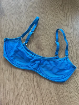 Lounge 💙 - Snygg blå mesh-bh från Lounge i storlek XS. Den har justerbara axelband och är tillverkad i ett lätt och luftigt material med Lounge-loggan diskret tryckt över hela tyget 💙