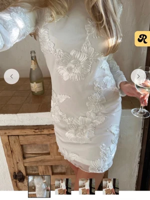 STUDENTKLÄNNING By IC - Supersnygg vit kortklänning från By IC med stora blommiga broderier. Klänningen har långärmad design. Perfekt till studenten!! Helt ny med prislapp kvar🩷