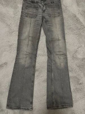 Grå bootcut jeans med stora fickor - Säljer ett par grå bootcut jeans med markerade sömmar och stora fyrkantiga fickor framtill. Jeansen har en lätt tvättad look och klassisk femficksdesign. Är köpta på Gina Tricot och storleken är 164, men passar också mig som är 170. 