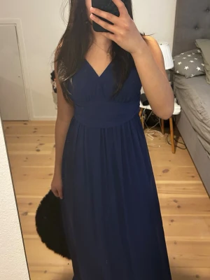 Marinblå balklänning med v-ringning - Super fin balklänning! Använd en gång, den är lite tight precis vid armhålorna men funkar! Den är lång på mig som är ca 153. Orginalpris 2000. Pris går att diskutera! Perfekt inför balen i våren!