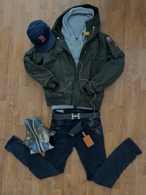 Mörkgrön Parajumpers hoodiejacka  - Snygg mörkgrön Parajumpers hoodiejacka med luva och dragkedja framtill. Jackan har flera fickor, ribbade muddar och en patch på ena ärmen. Perfekt för en avslappnad streetwear-look.